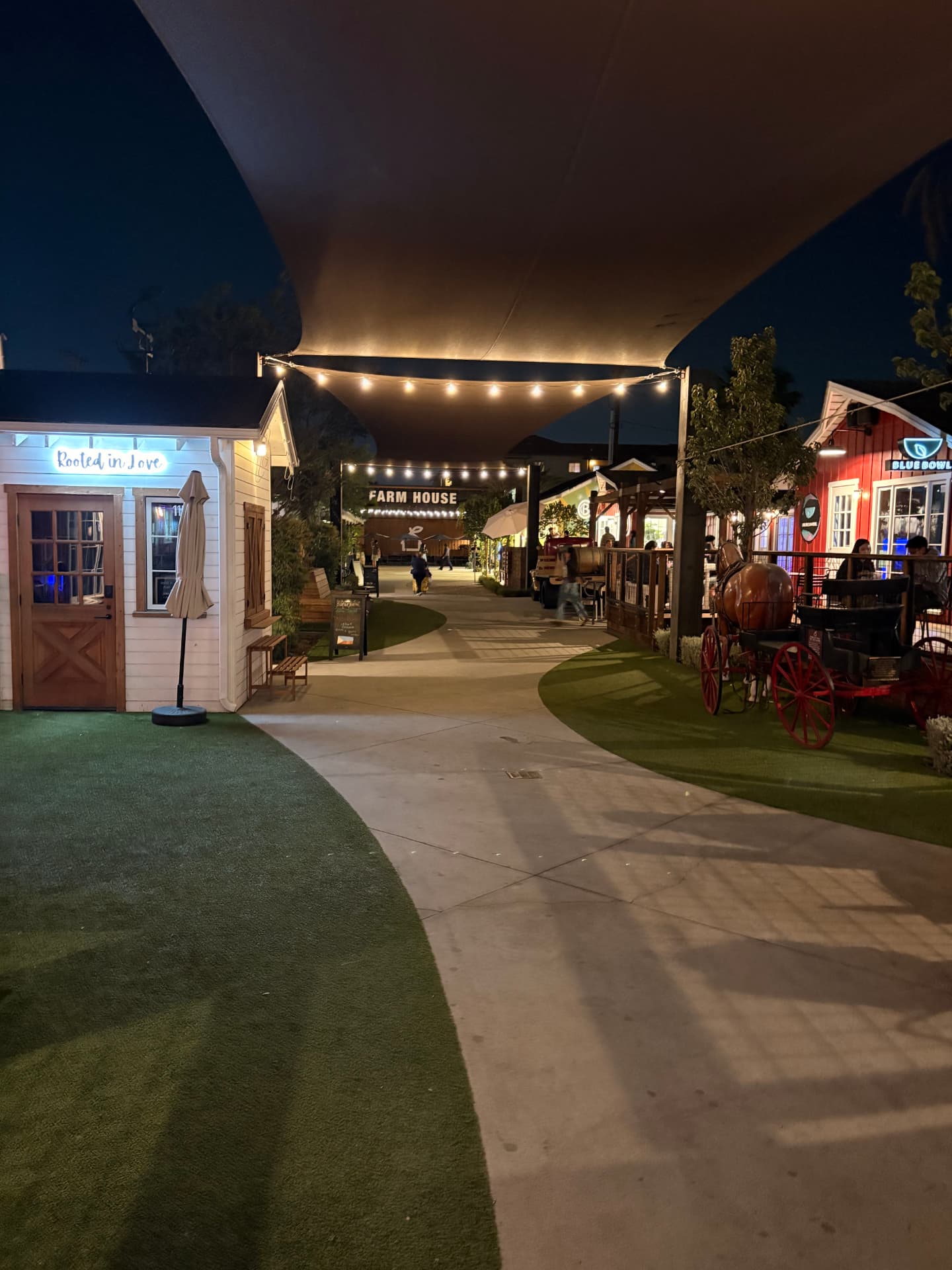 The Farm House Collective walkway at night with dining and gathering spaces