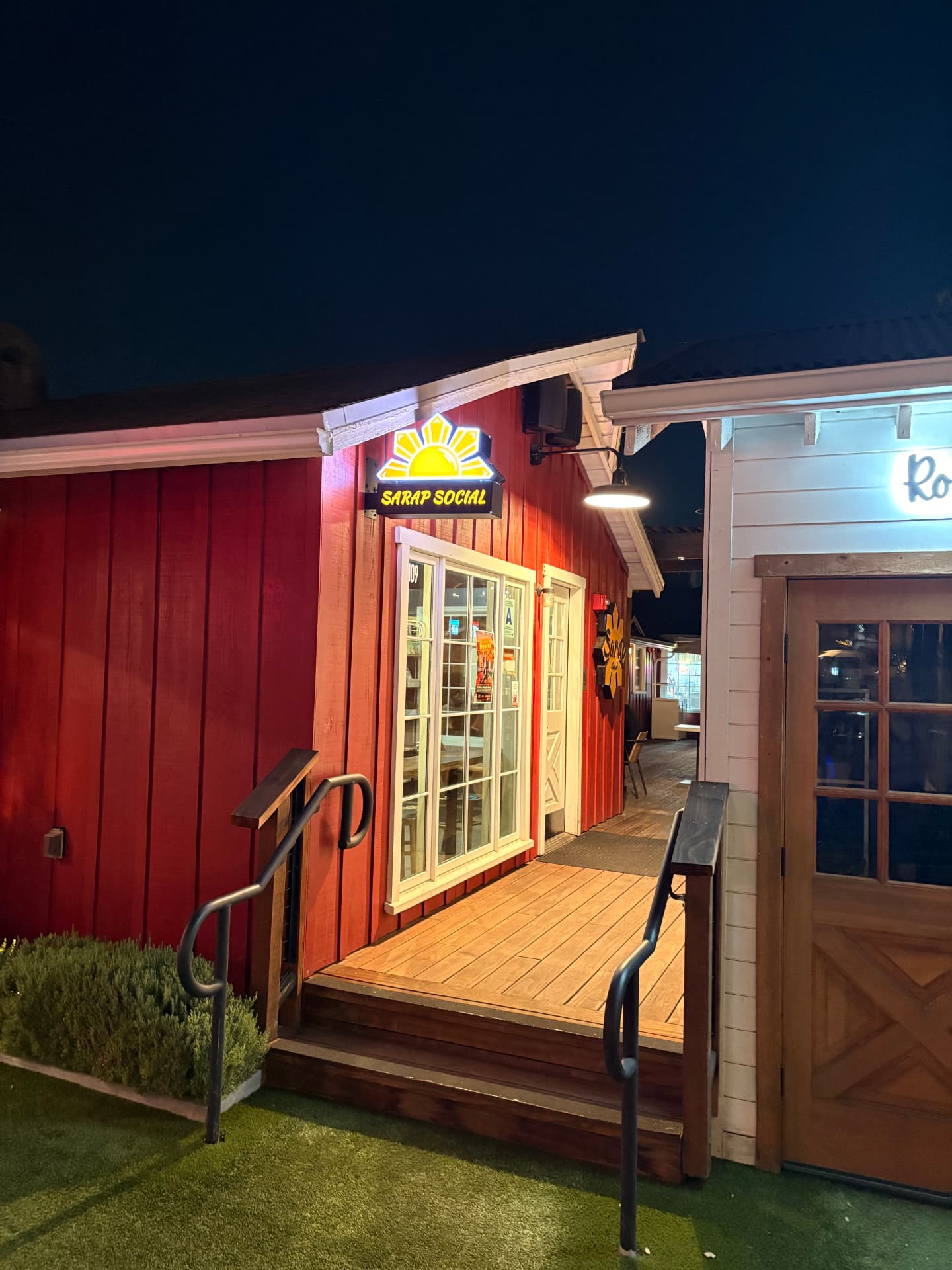 The illuminated Sarap Social storefront inside Farm House Collective at night